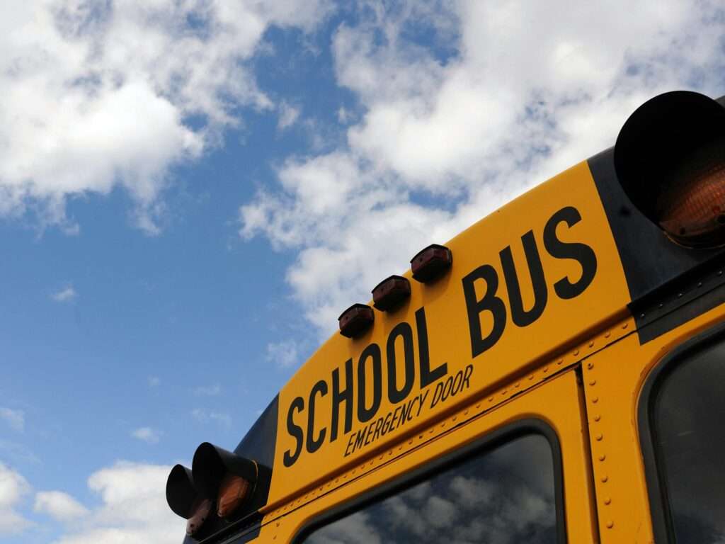 Close-up shot of a yellow school bus with a blue sky background, showcasing cloud formations.